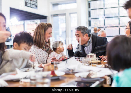 Grand-père gâteau d'alimentation pour bébé fille tout en étant assis en famille dans le Banque D'Images