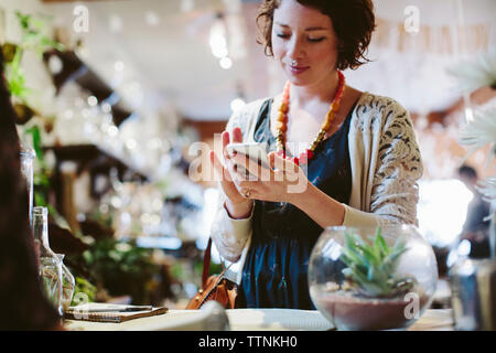 Portrait de propriétaire avec le client à l'aide de téléphone mobile pour le paiement en magasin de l'usine Banque D'Images