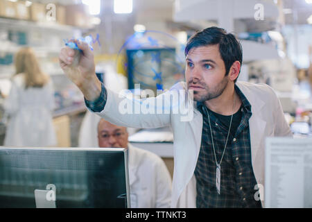 Médecin homme écrit sur la fenêtre en verre avec les collègues de travail en arrière-plan dans les prix Banque D'Images