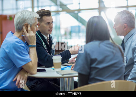 Les médecins de discuter tout en étant assis à table dans la salle médicale Banque D'Images