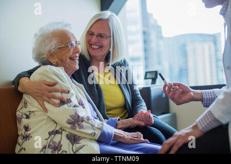 Happy female patient avec fille parlant à male doctor in hospital ward Banque D'Images