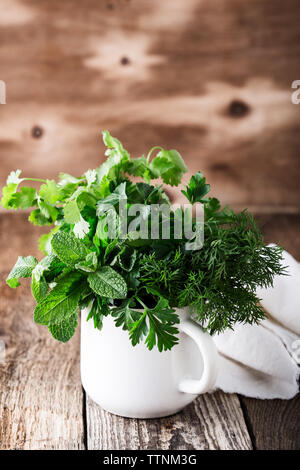 Les frais menthe bio, aneth, persil, coriandre. et d'herbes aromatiques culinaires dans l'usine rurale blanc mug sur table en bois, jardins familiaux, Close up, Banque D'Images