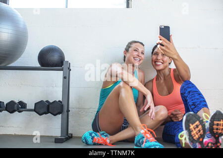 Happy female friends par selfies téléphone mobile en salle de sport Banque D'Images