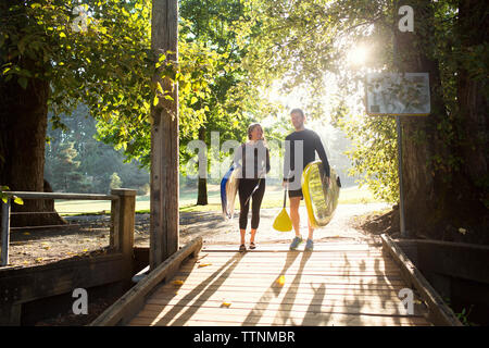 Couple avec paddleboards marche sur boardwalk Banque D'Images