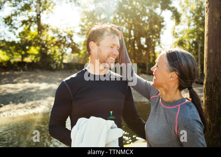 Happy woman tirant les cheveux de l'homme debout par river Banque D'Images