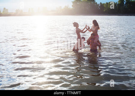 Amis Hommes Femmes portant sur les épaules tout en appréciant en rivière Banque D'Images
