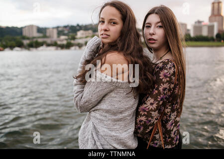 Portrait of female friends standing contre river in city Banque D'Images