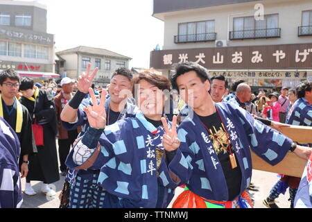 Les jeunes hommes de célébrer et de rire après avoir poussé flotte dans le festival Inuyama montrant le geste de paix deux doigts Banque D'Images