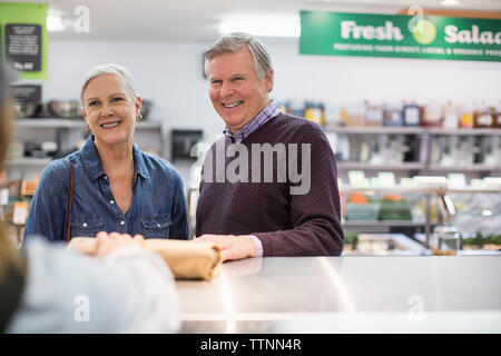 Portrait of woman giving paquet à senior couple at supermarket Banque D'Images