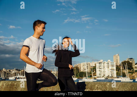 Happy young couple exerçant sur la promenade contre ciel en ville Banque D'Images