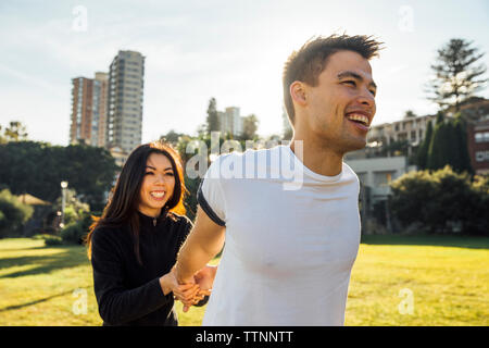 Petite amie d'aider son petit ami dans les mains d'étirement sur terrain en ville Banque D'Images