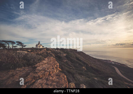 Vue éloignée du vieux phare de Point Loma sur mountain contre ciel nuageux pendant le coucher du soleil Banque D'Images