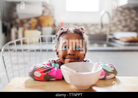 Portrait of cute girl leaning on table avec petit déjeuner bol en premier plan Banque D'Images