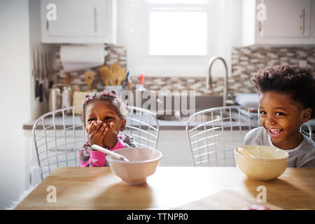 Cheerful frère et sœur à l'écart pendant le petit-déjeuner dans la cuisine Banque D'Images