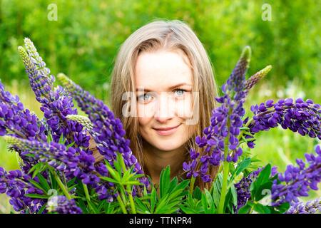 Belle et jeune fille parmi les belles fleurs de lupins. Elle aime le moment d'être parmi un groupe de fleurs de teinte pourpre. Banque D'Images