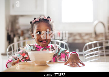 Cute girl faire face pendant le petit-déjeuner dans la cuisine Banque D'Images