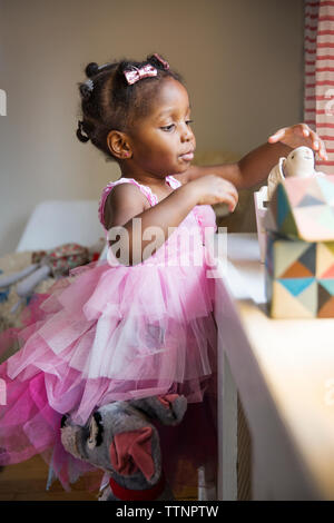 Jolie fille en robe rose dépose toy à partir de fort à la maison Banque D'Images