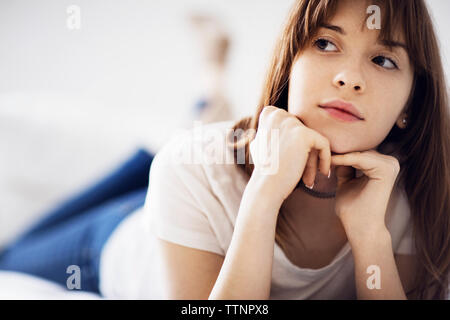 Young woman lying on bed at home Banque D'Images
