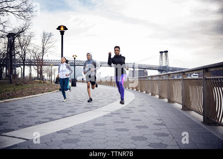 Les athlètes multi-ethnique dédié exécutant sur sentier avec Williamsburg Bridge en arrière-plan Banque D'Images