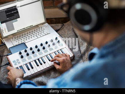 High angle view of man playing piano par ordinateur portable à la maison Banque D'Images