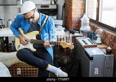 L'homme qui joue de la guitare à la maison Banque D'Images