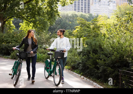 Couple de parler tout en marchant sur le sentier avec des bicyclettes Banque D'Images