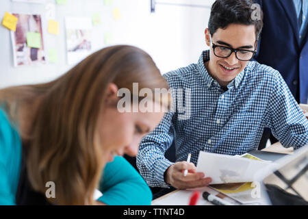 Happy business people discussing over photos at desk in office Banque D'Images
