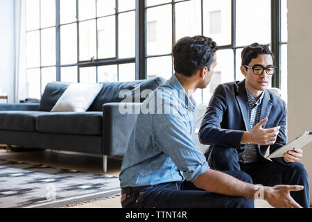 les gens d'affaires discutent sur tablette numérique assis dans le bureau Banque D'Images