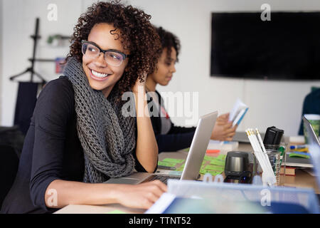 Smiling businesswomen with colleague at conference table dans la salle du conseil d'administration Banque D'Images