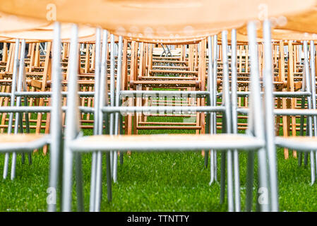 Chaises en bois close-up stand en extérieur dans le parc sous la pluie. Empty auditorium, l'herbe verte, des arbres et des chaises avec des gouttes d'eau. Banque D'Images