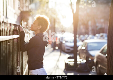 Jeune femme peeking sur rambarde en se tenant sur le trottoir Banque D'Images