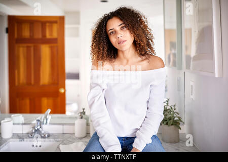 Portrait de femme assise en miroir dans salle de bains à la maison Banque D'Images