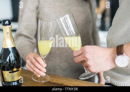 Portrait couple toasting drinks at table in kitchen Banque D'Images