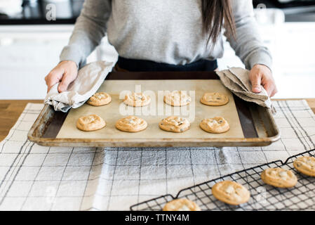 Midsection of woman holding cookies au-dessus de la table de cuisson dans la cuisine Banque D'Images