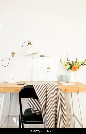 Avec calendrier et technologies de bureau lampe par flower vase on table in office Banque D'Images