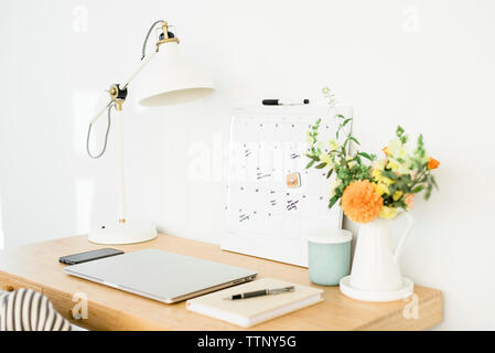 Technologies de lampe de bureau avec calendrier et par vase à fleurs sur table en bois contre wall in office Banque D'Images