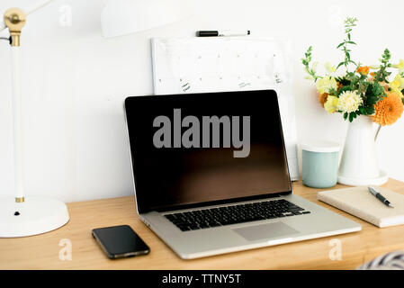 Technologies de lampe de bureau avec calendrier et par vase à fleurs sur table en bois in office Banque D'Images