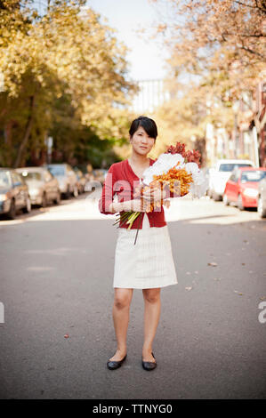 Portrait de propriétaire holding bouquets en se tenant sur le road Banque D'Images