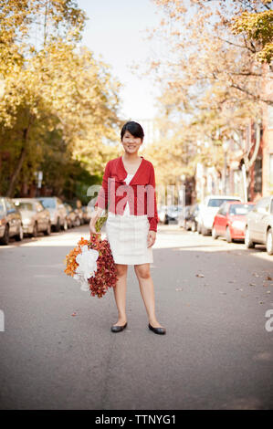Portrait de femme propriétaire holding bouquets en se tenant sur le road Banque D'Images