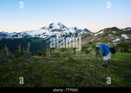 Man photographing snowcapped mountain en se tenant sur le terrain herbeux Banque D'Images