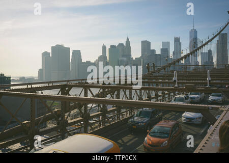 Portrait de véhicules sur pont de Brooklyn contre city skyline Banque D'Images