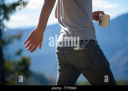 Portrait man holding Coffee cup lors de la marche en forêt durant les jours ensoleillés Banque D'Images