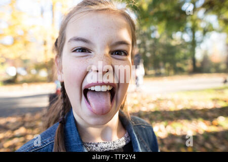 Close-up portrait of girl sticking out tongue while standing at park Banque D'Images