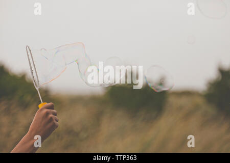 Cropped hand of man holding bubble wand sur terrain Banque D'Images