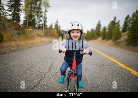 Portrait of cute cheerful baby boy riding bicycle on country road Banque D'Images