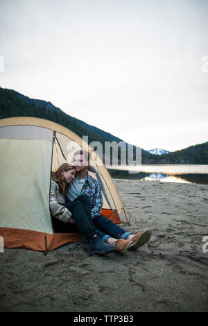 Young couple sitting in tent sur Lakeshore à Silver Lake Provincial Park Banque D'Images