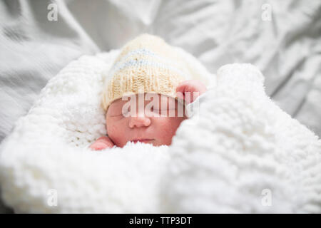 De baby girl wearing Knit hat sleeping on bed at home Banque D'Images