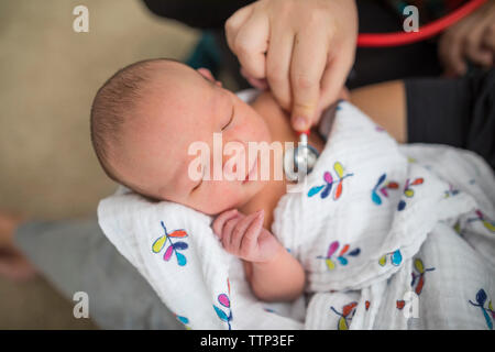 La main coupée de sage-femme examining newborn baby girl porté par la mère à la maison Banque D'Images