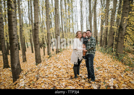 Portrait of smiling family standing contre les troncs des arbres en forêt en automne Banque D'Images