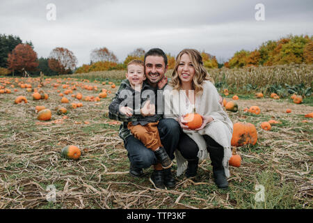 Portrait de famille heureuse accroupi sur citrouille en automne Banque D'Images